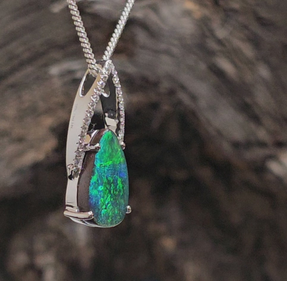 Video showing white gold necklace with diamonds and a dark blue and green boulder opal spin.