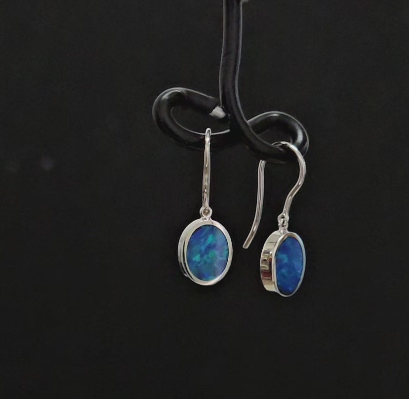 Vivid blue oval shaped opals in classic shepherd hook earrings set in white gold.